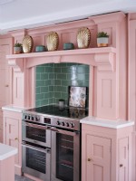 cuisine faite à la main avec des unités peintes en rose avec cuisinière en acier inoxydable
