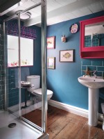 Salle de bain bleue avec œuvres d'art et miroir rose