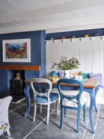 Salle à manger avec des couleurs d'inspiration côtière et une cheminée avec des œuvres d'art marines au-dessus