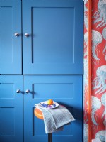 Unités de cuisine bleues modernes avec un papier peint inspiré de la mer et un tabouret orange