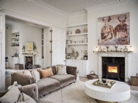Salon ouvert neutre avec cheminée, tissus d'ameublement beige et table basse circulaire