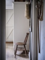 Vue depuis la porte avec une chaise marron rustique et une armoire blanche