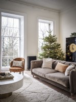 Grand canapé gris et tapis crème devant le sapin de Noël