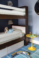 Chambre bleue pour garçons avec lits superposés et tapis coloré à motifs carrés.