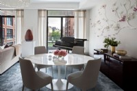 Table à manger, chaises et piano dans un espace de vie ouvert avec vue sur la ville.
