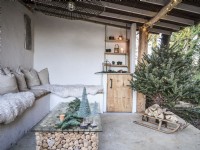 Espace extérieur avec décor de Noël et bûches empilées sous la table basse