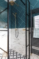 Cabine de douche avec portes de style crittall, pommeau de douche en laiton, carreaux de marbre et carreaux bleu sarcelle