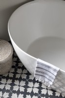 Détail d'une baignoire autoportante contemporaine avec des carreaux à motifs noirs et blancs audacieux