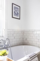 Détail de la baignoire autoportante, du mélangeur de bain chromé et des carreaux de marbre