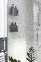 Détail de la cabine de douche avec carreaux de métro en marbre et solution de stockage de bouteilles