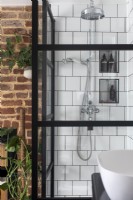 Douche avec portes de style crittall noires, tuiles carrées blanches et pomme de douche chromée.
