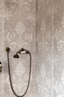 Détail de la douche, carreaux à motifs roses et douche en laiton