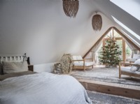 Chambre loft à plan ouvert dans des tons neutres avec des sièges et un arbre de Noël