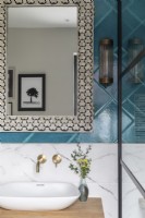 Détail de l'évier avec carreaux de marbre et de couleur sarcelle, robinets en laiton et miroir incrusté marocain