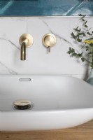 Détail de la vasque et des robinets en laiton avec des carreaux de marbre et de couleur sarcelle