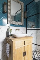 Détail de la vanité et de l'évier en bois avec robinets en laiton, miroir de style marocain et carreaux audacieux.