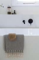 Détail d'une baignoire contemporaine autoportante avec robinets noirs.