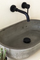 Gros plan sur un évier en béton et des robinets noirs