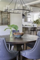 Table à manger ronde en bois et chaises rembourrées dans la salle à manger et la cuisine à aire ouverte.