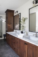 Salle de bain moderne avec double vasque et armoires en bois marron.
