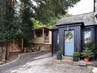 Cabane de campagne avec porte bleue et bardage en bois noir