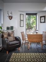 Chambre du milieu du siècle avec tapis rétro, fauteuil en cuir et table à manger en bois
