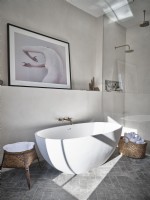 Salle de bain aux tons neutres avec baignoire blanche et paniers en osier