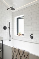 Salle de bain carrelée blanche avec accessoires noirs