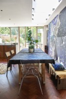 Une table à manger avec une nappe à motifs bleus design à côté d'un mur de papier peint design.