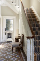 Couloirs avec sol carrelé d'origine et escaliers avec tapis à rayures.