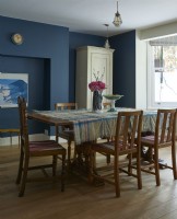 Table et chaises de salle à manger rétro dans une pièce peinte en bleu foncé.
