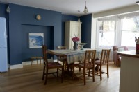 Table et chaises de salle à manger rétro dans une pièce peinte en bleu foncé.