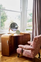 Une coiffeuse pliante faite à la main par un designer dans une baie vitrée avec une chaise ancienne recouverte de tissu William Morris.