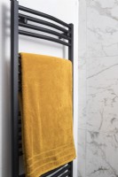 Détail du radiateur sèche-serviettes noir avec serviette jaune moutarde