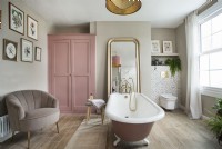 Salle de bain féminine de style vintage avec baignoire à roulettes rose et armoire