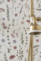 Mur floral et pommeau de douche doré dans la salle de bain féminine - détail