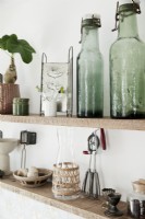 Détail des étagères de cuisine en bois ouvertes avec des collections de bouteilles et d'accessoires en verre vintage