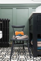 Détail d'une petite chaise de salle de bain sur un sol en carrelage à motifs monochromes