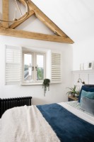 Vue sur lit à fenêtre avec volets de plantation dans une chambre de style campagnard