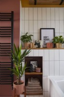 Détail de la salle de bain avec porte-serviettes noir, carrelage blanc et mur peint en rose.