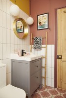 Salle de bain avec sol en vinyle coloré, carrelage blanc et murs peints en jaune et rose.