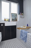 Détail de la salle de bain avec carrelage blanc carré, murs et armoires gris.