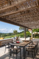 Salle à manger extérieure ombragée sur terrasse avec vue panoramique en été