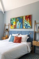 Œuvres d'art colorées au-dessus du lit dans une chambre moderne