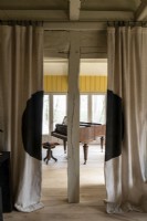 Voir à travers les rideaux au piano à queue dans la maison de campagne