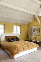 Chambre de campagne moderne avec des murs en bois peints en jaune