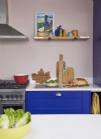 Détail de cuisine coloré avec armoires bleu cobalt et étagères ouvertes.