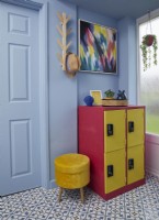 Hall d'entrée peint en bleu avec des casiers jaunes et roses et un sol carrelé.