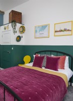 Chambre avec un mur peint en vert et une literie violette.