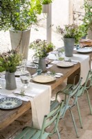Table de salle à manger extérieure rustique dressée pour le déjeuner avec des compositions florales